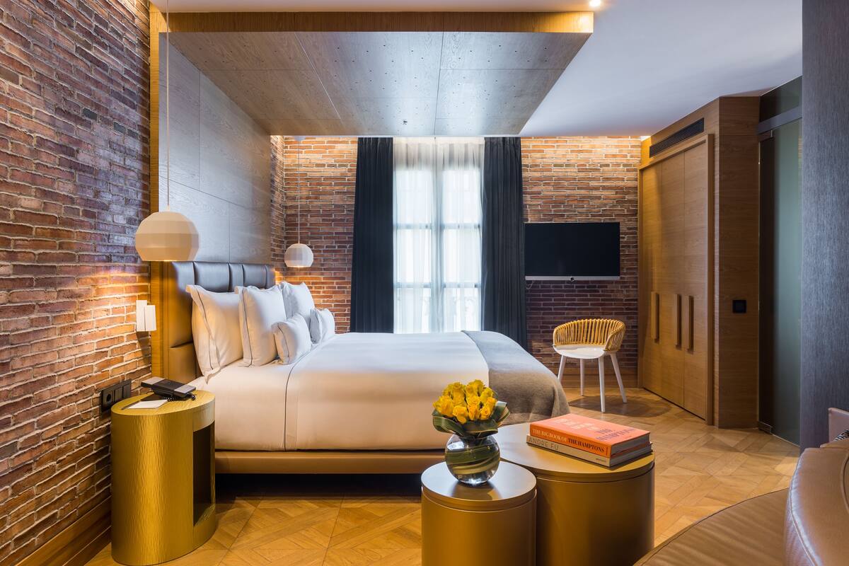 Un dormitorio moderno con pared de ladrillo, una cama grande, un televisor de pantalla plana y un armario de madera.