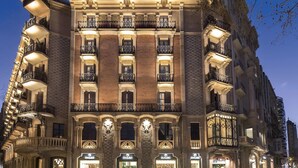 Un edificio de varios pisos con balcones ornamentados y ventanas iluminadas, que sugiere una propiedad histórica o de interés arquitectónico.