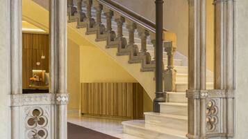 Una gran escalera con columnas ornamentales y un acabado de mármol, que conduce a un piso superior.