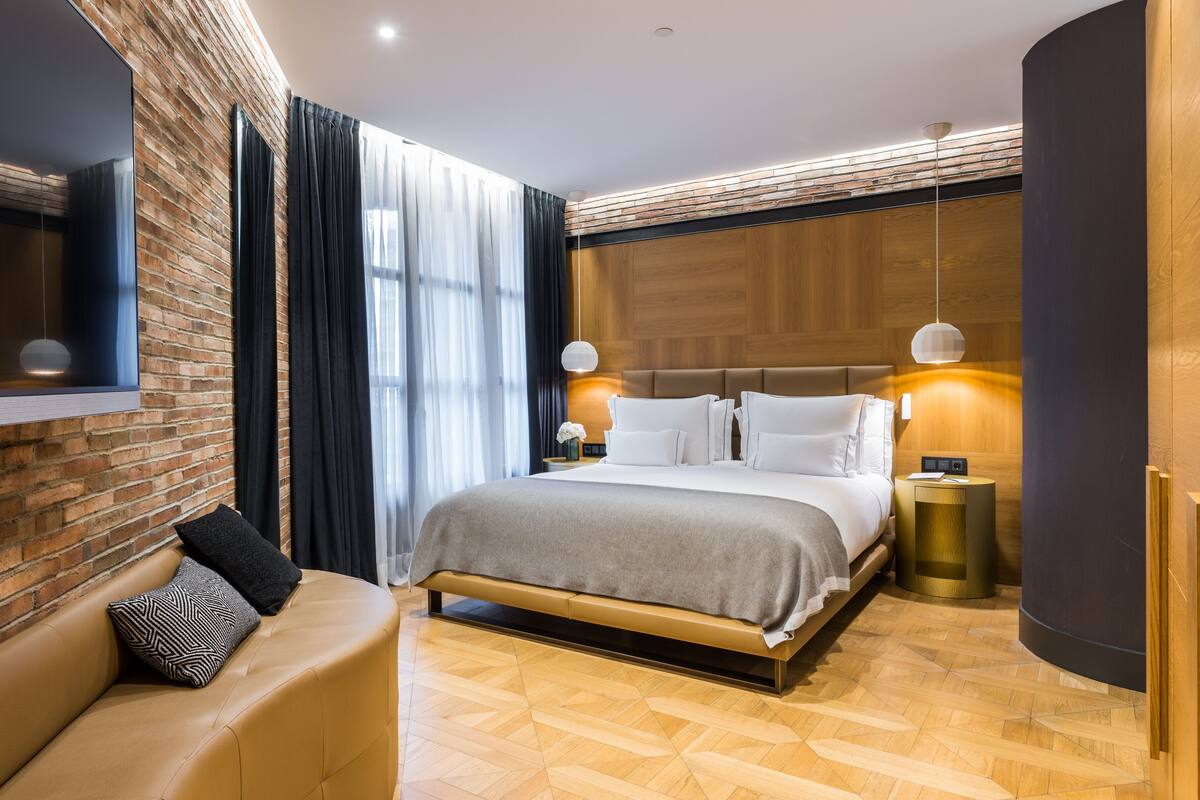 Un dormitorio moderno con una cama grande, un sofá y un espejo.
