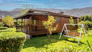 A wooden cabin with a porch, surrounded by lush greenery and mountains in the background. - Ikiz Villas (Kemer)