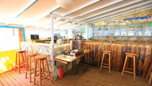 A bar area with wooden stools, a stone counter, and a stone wall backdrop. - Ikiz Villas (Kemer)