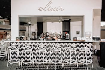 A reception desk with a modern design, a large abstract wall mural, and a dark floor. at V Capri Palm Springs, a Dolce by Wyndham