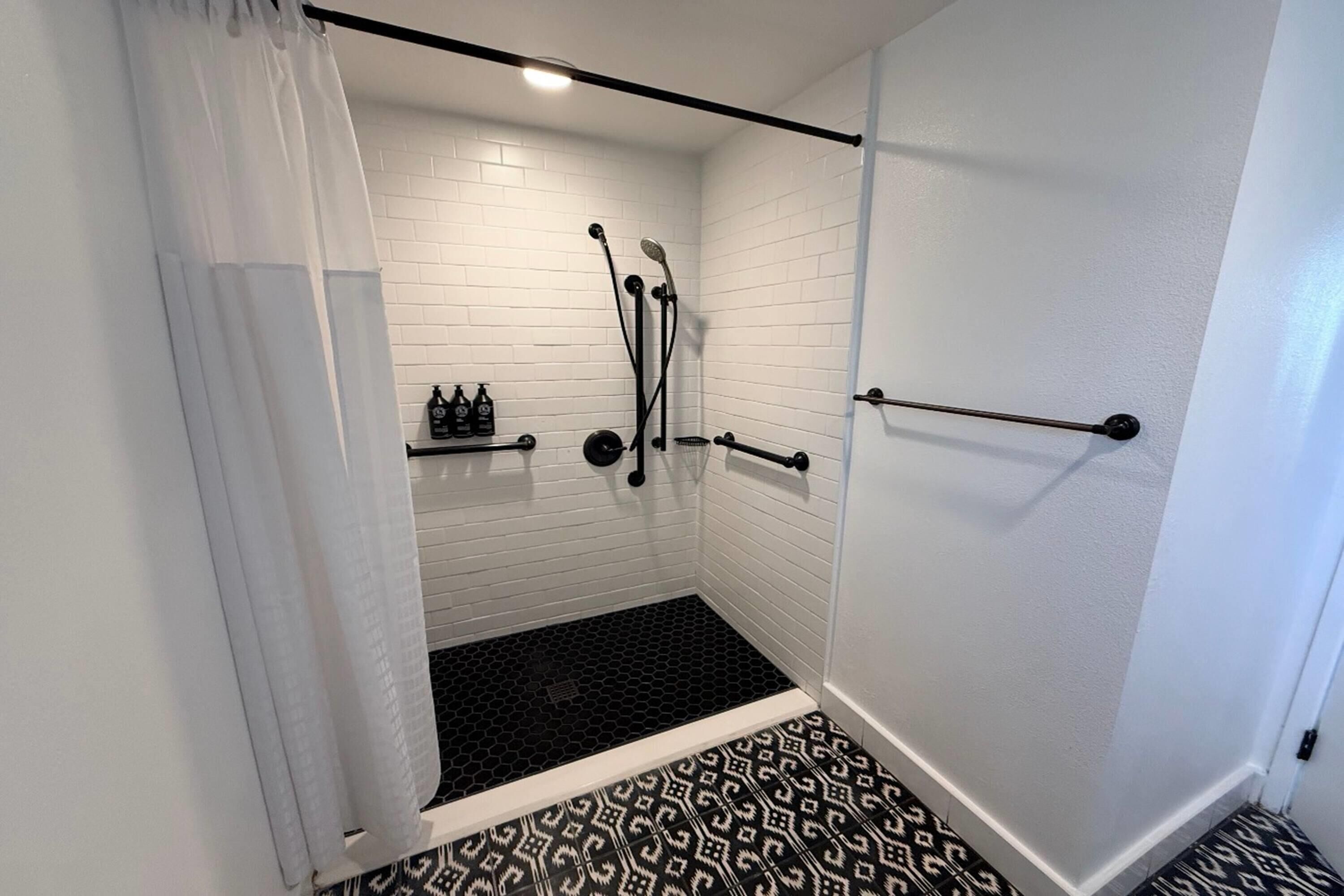 A shower with a black floor, white walls, and a white curtain.