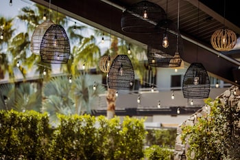 A stone wall with potted plants and a geometric-patterned bench. at V Capri Palm Springs, a Dolce by Wyndham