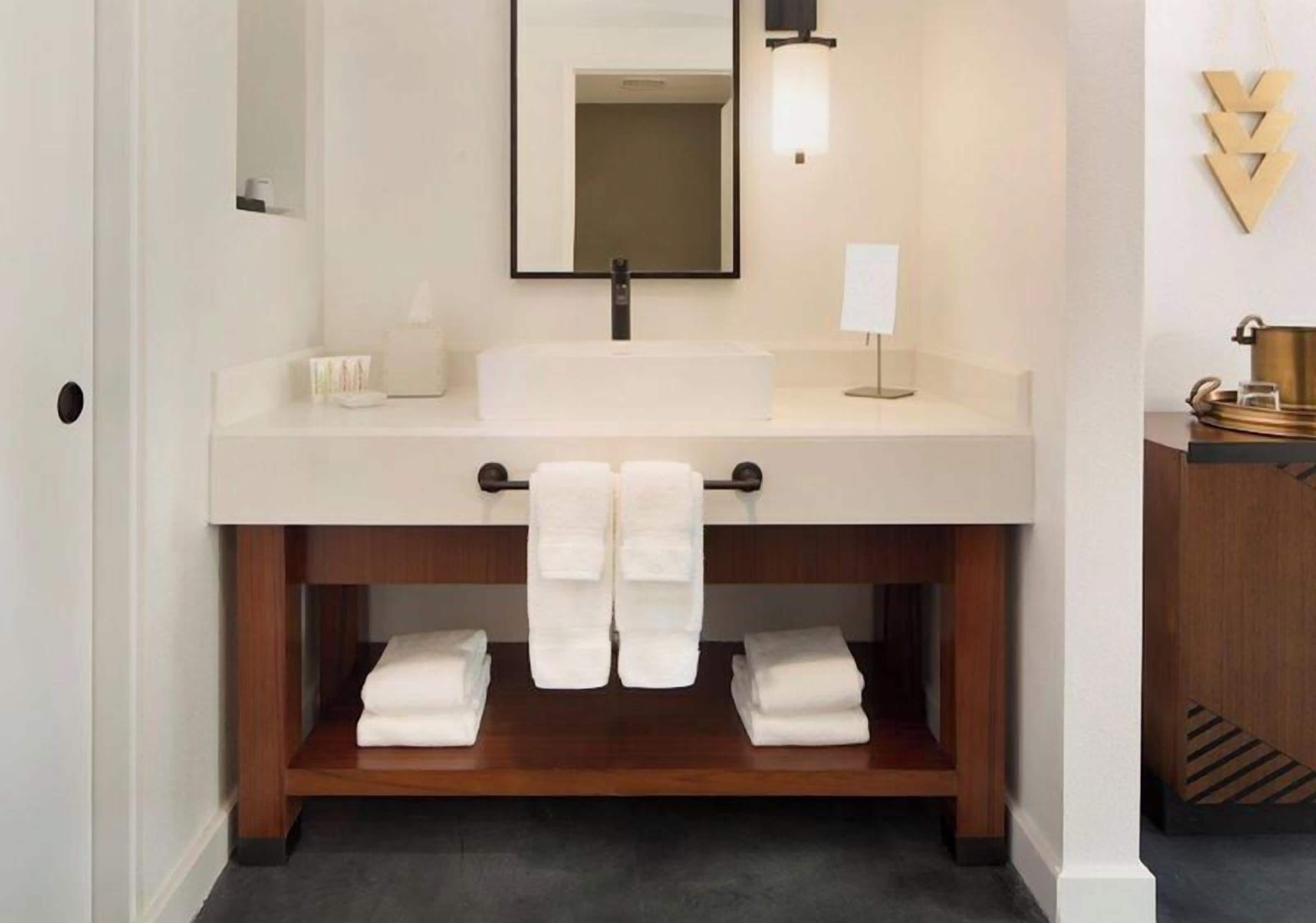 A bathroom with a white sink, a mirror, and a towel rack.