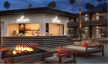 A modern interior with a large black lamp, a sofa, a coffee table, and a bookshelf. at V Capri Palm Springs, a Dolce by Wyndham