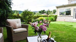 A wicker sofa and a glass table with a bottle of champagne and glasses. - Craigmhor Lodge & Courtyard (Pitlochry)