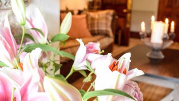 Una habitación con un arreglo floral, un sofá y velas encendidas.