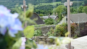 A view of a stone wall and a wooden deck with a stone wall in the foreground. - Craigmhor Lodge & Courtyard (Pitlochry)