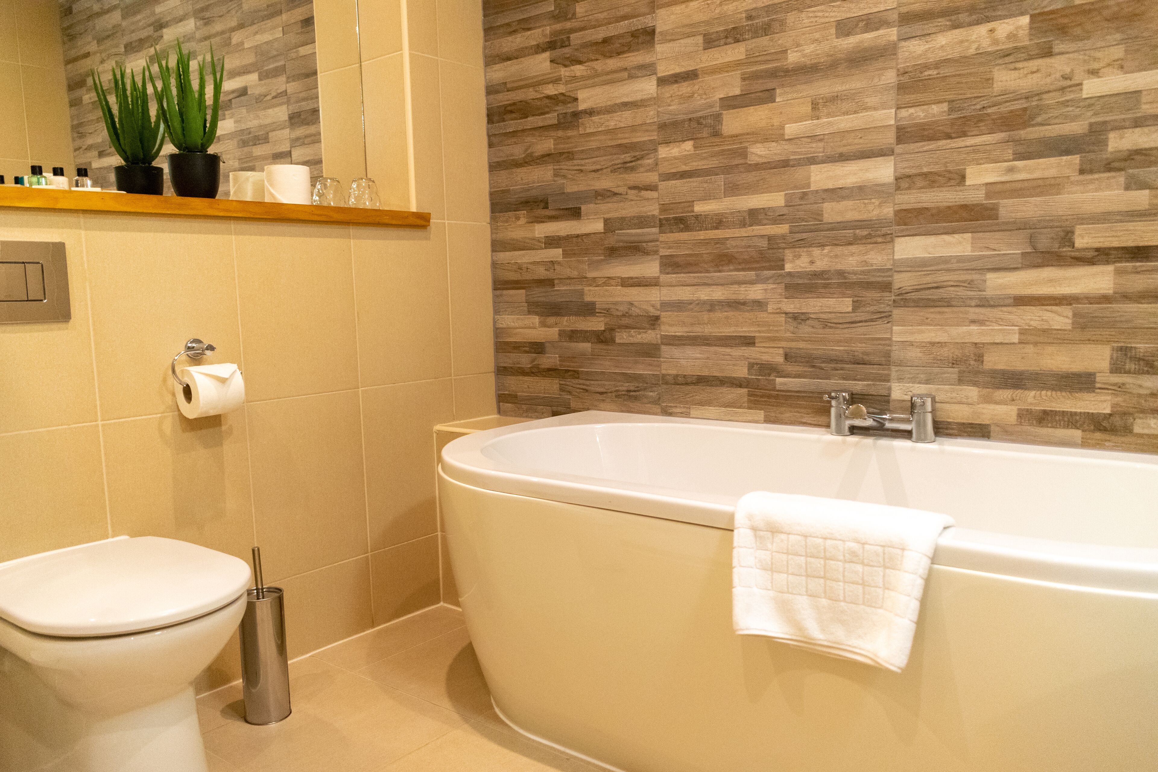 Une salle de bain avec des toilettes, un lavabo, une baignoire et un mur en bois.