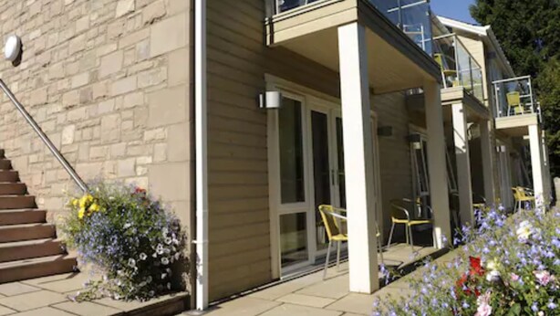 A modern building with a glass balcony, a staircase, and outdoor seating. - Craigmhor Lodge & Courtyard (Pitlochry)