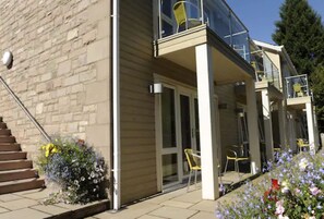 A modern building with a glass balcony, a staircase, and outdoor seating. - Craigmhor Lodge & Courtyard (Pitlochry)