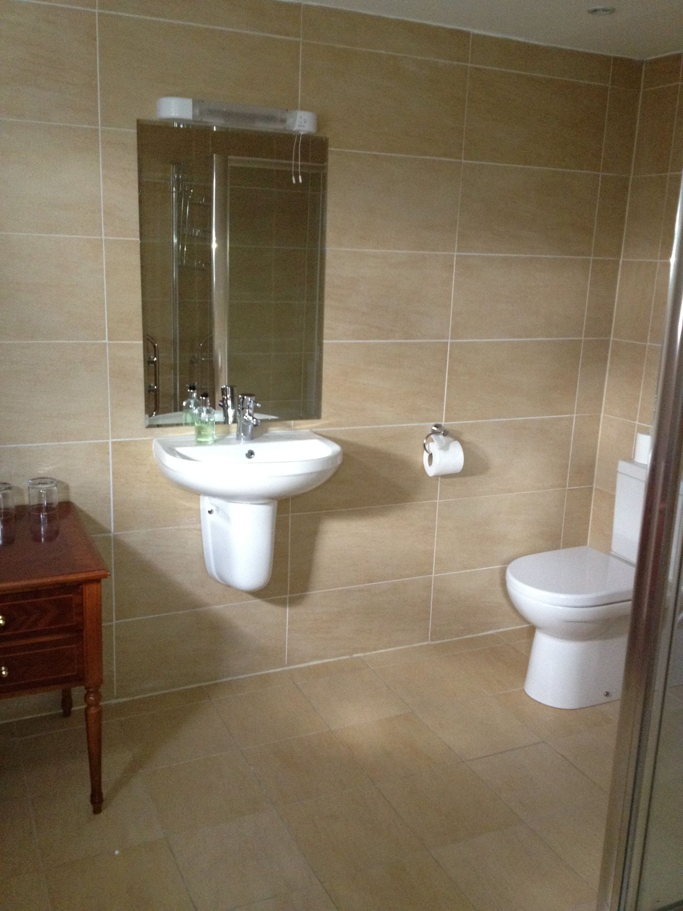 Ein Badezimmer mit Waschbecken, Spiegel, Toilette und einem Holzschrank.