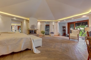 Une chambre spacieuse avec un grand lit, un plancher en bois et une vue sur l’extérieur.