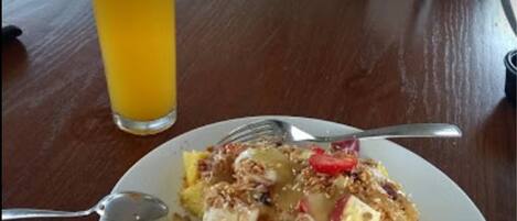 Een bord eten met een glas jus d'orange op een houten tafel.