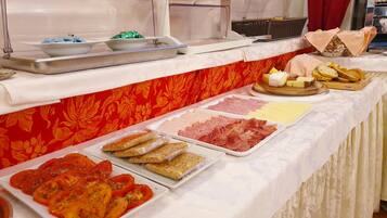 Una mesa de buffet con diversos alimentos, incluyendo carnes, quesos y pan.