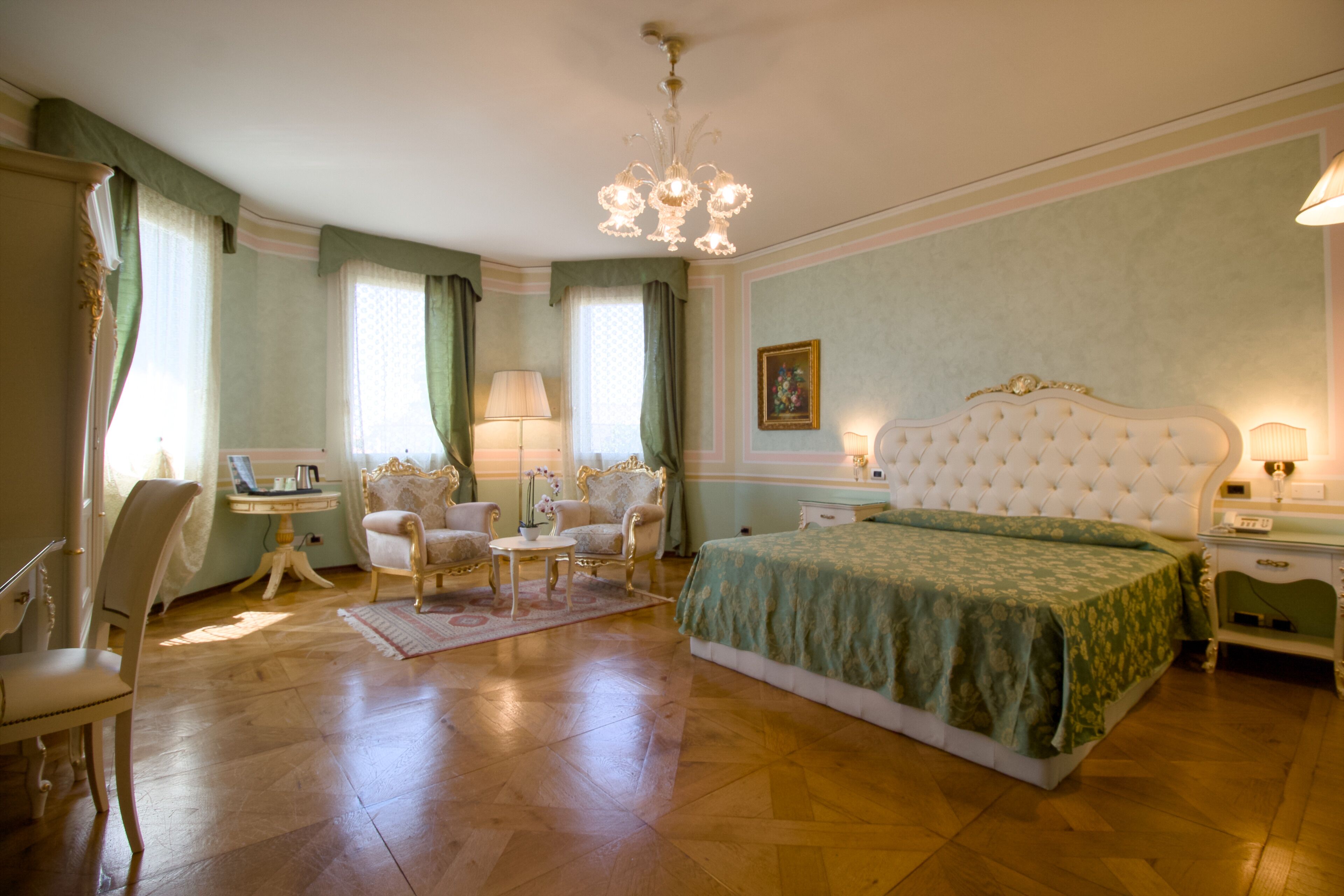 Une chambre spacieuse avec un grand lit, un coin salon avec une table et des chaises, et un lustre.