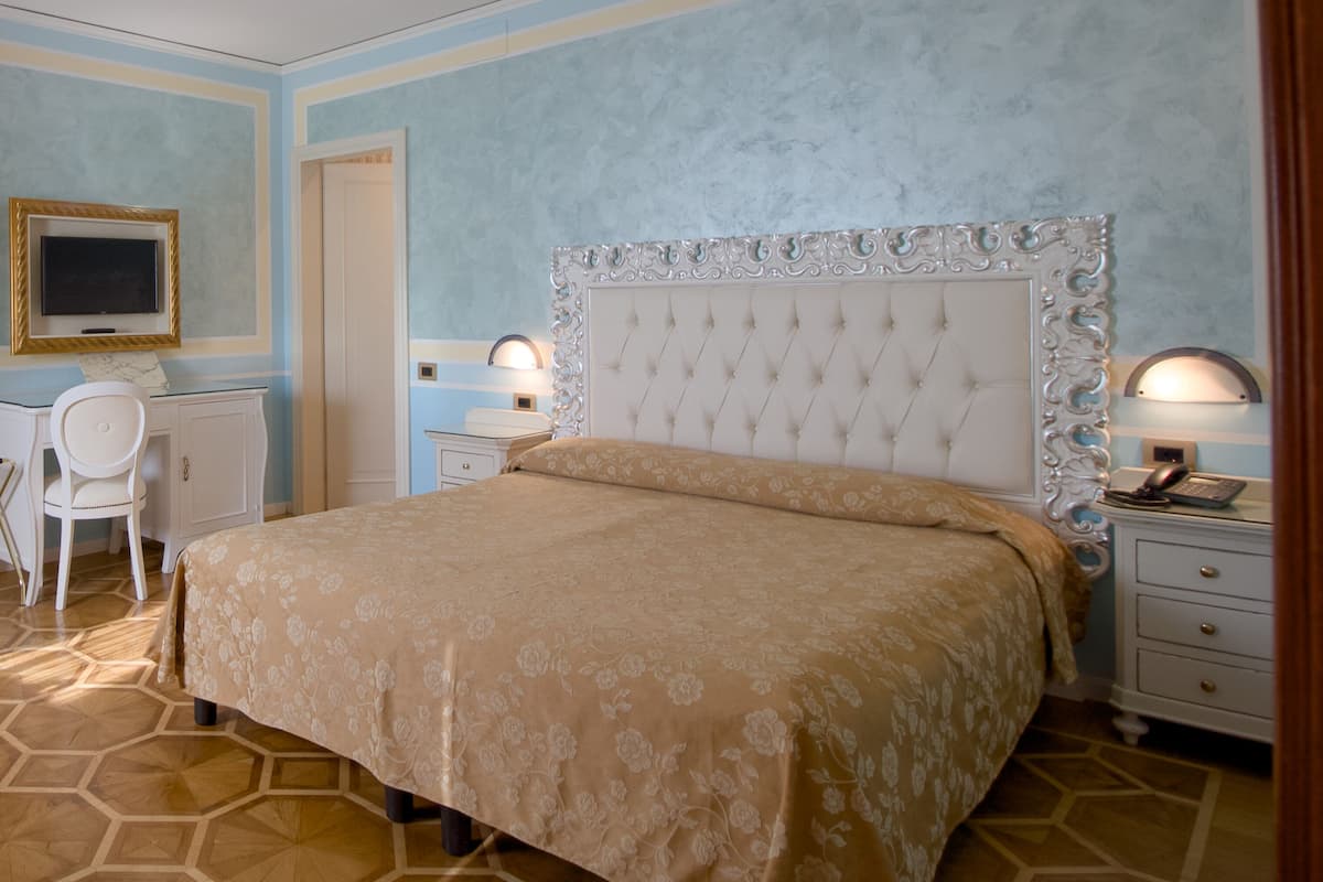 A bedroom with a large bed, a desk, and a chair.