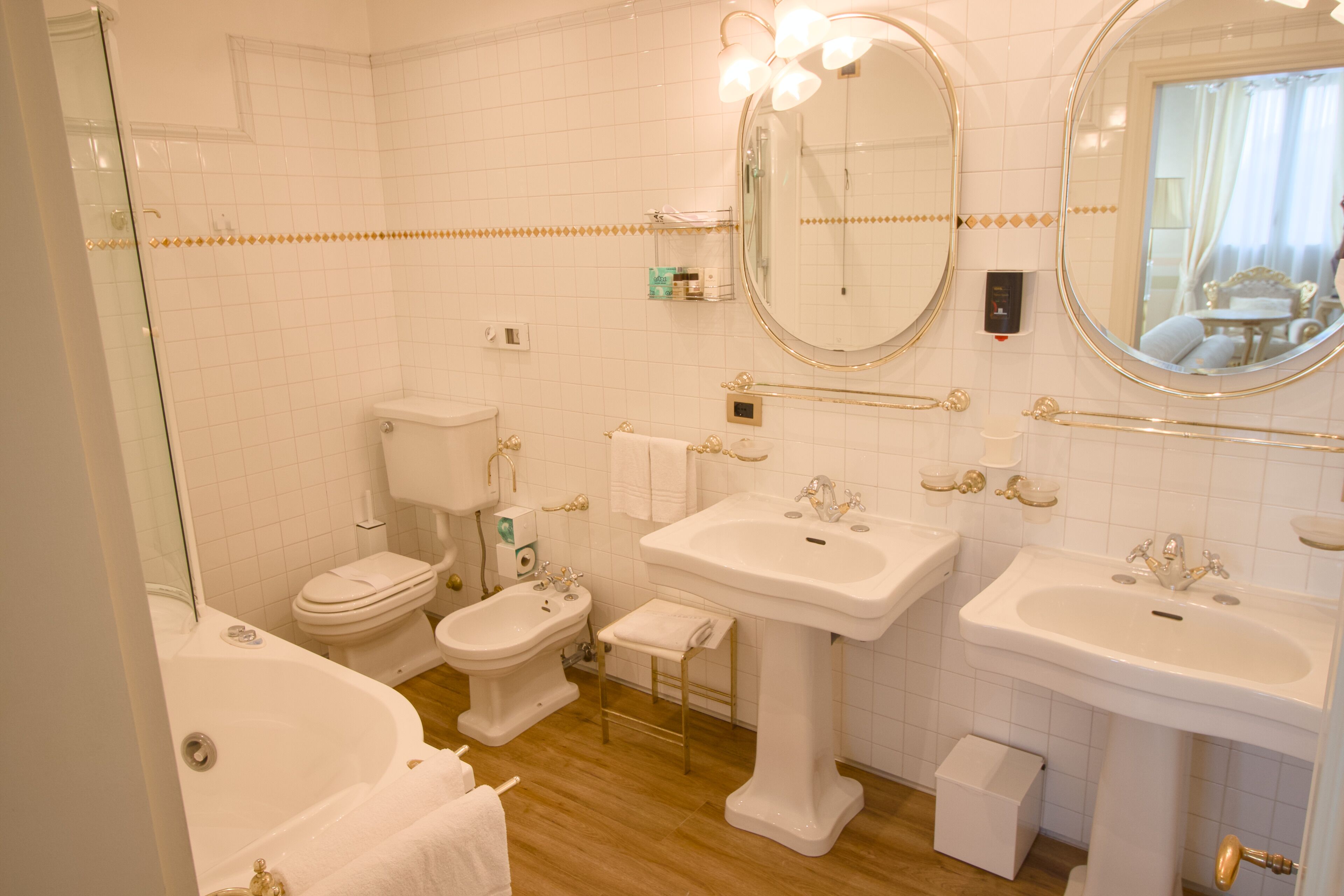 A bathroom with a bathtub, toilet, bidet, and two sinks.