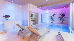 A modern indoor pool area with glass doors, lounge chairs, and potted plants. - MH Florence Hotel & Spa (Florence)
