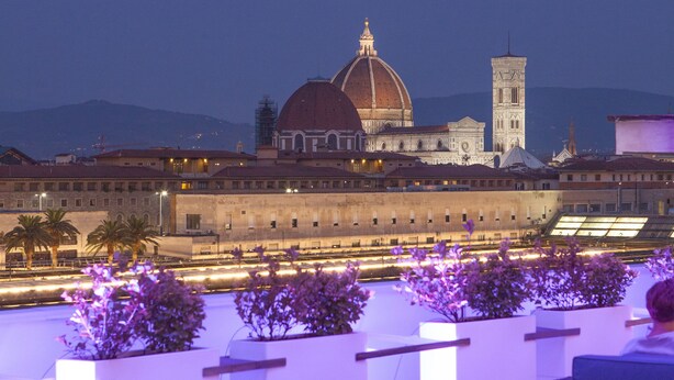 A rooftop terrace with wicker furniture and a view of a historic building with a dome and tower. - MH Florence Hotel & Spa (Florence)
