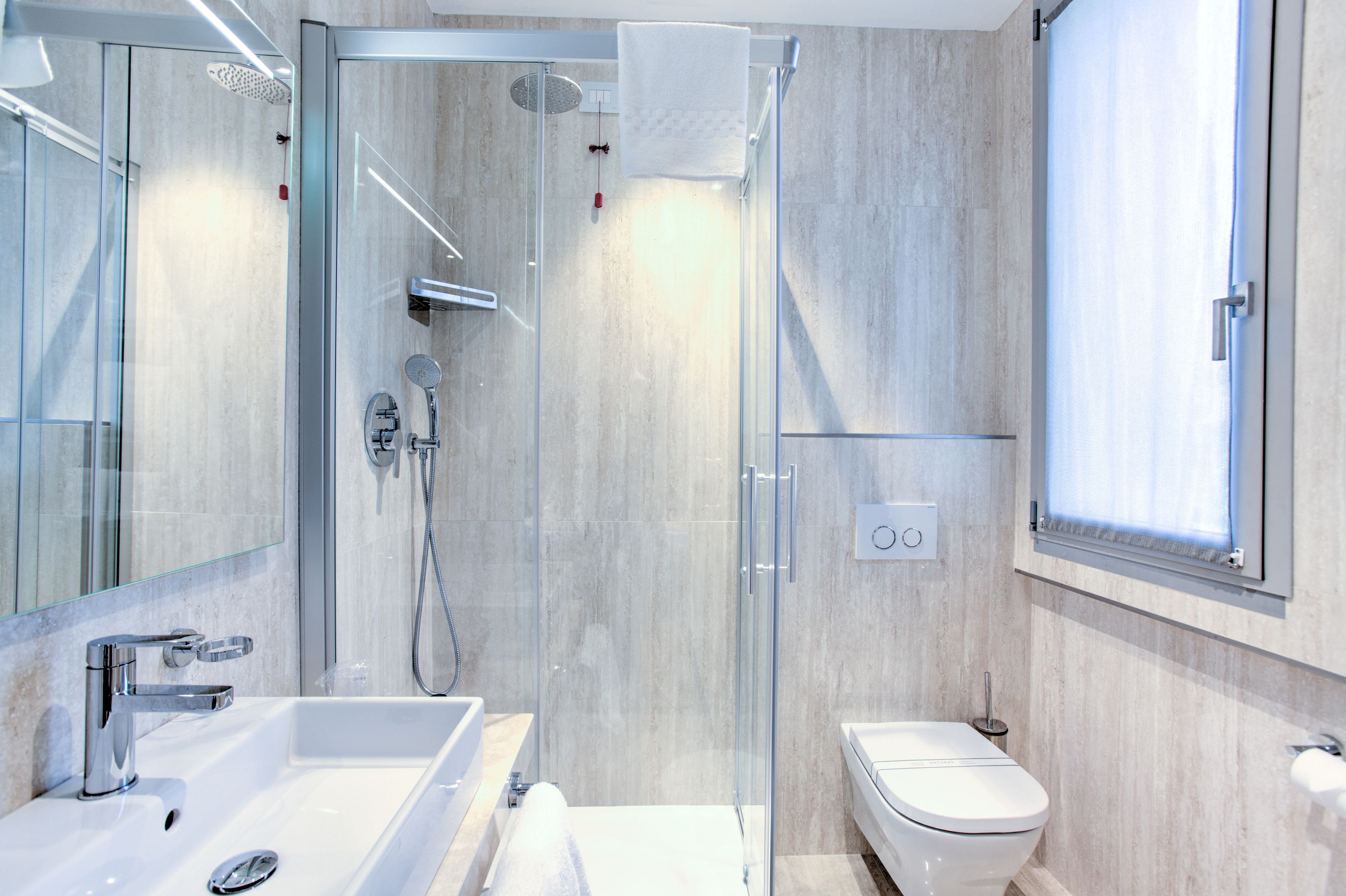 A modern bathroom with a glass-enclosed shower, a white sink, and a toilet.