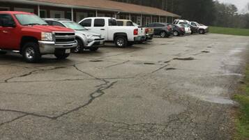 A parking lot with several vehicles, including trucks and cars, parked in front of a building with a brown roof.