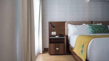 Habitación de hotel con cabecera de madera, una mesita de noche con lámpara, teléfono y un cajón pequeño.