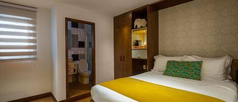 A hotel room with a bed, a bathroom, and a small kitchenette.