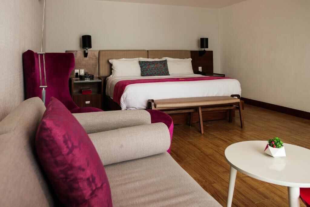 Een hotelkamer met een bed, een bankje, een klein tafeltje en een slaapbank.