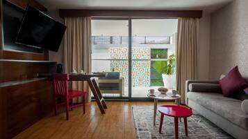 Un salon moderne avec un téléviseur à écran plat, un canapé, une table à manger et un fauteuil rouge.