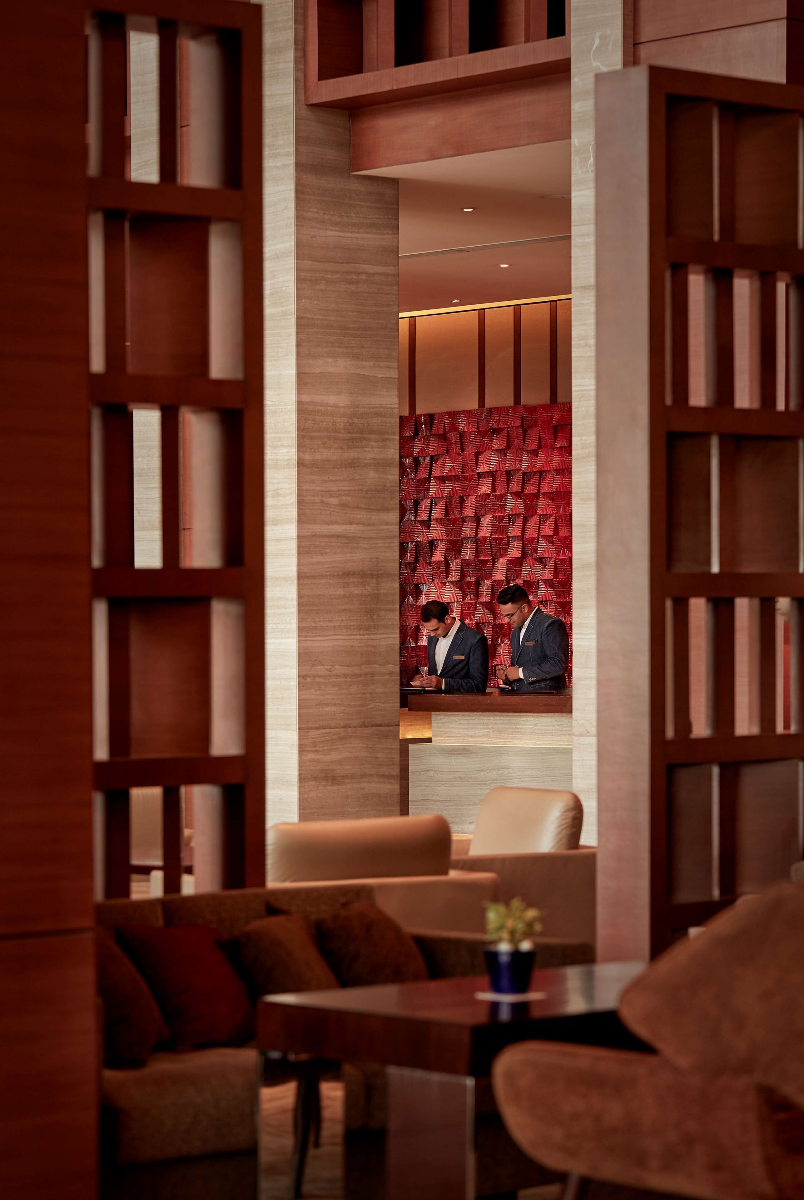 A modern lobby with a central seating area, wooden bookshelves, and a patterned wall.