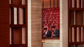 A modern lobby with a central seating area, wooden bookshelves, and a patterned wall.