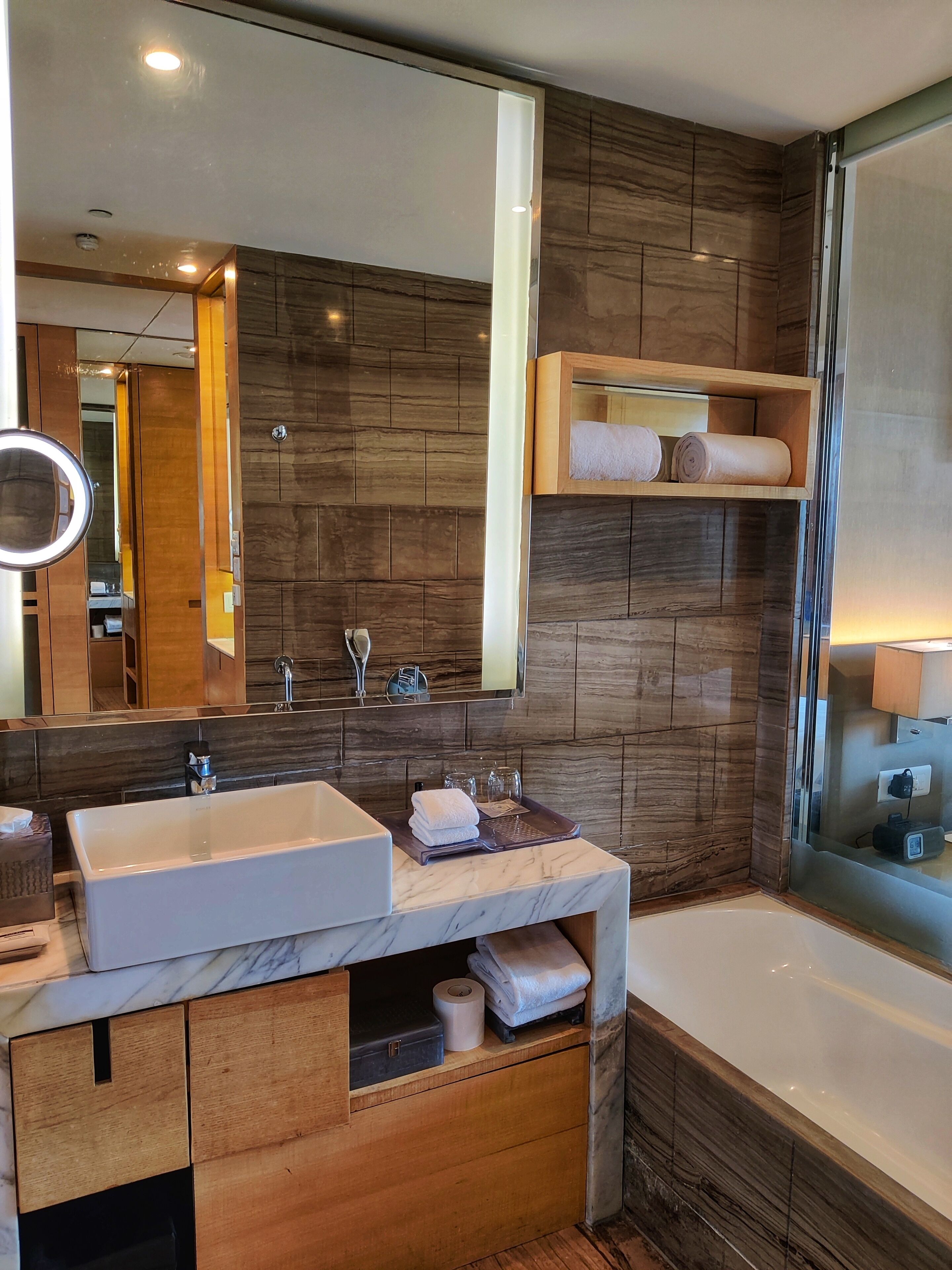 Une salle de bain moderne avec un grand miroir, deux lavabos, une baignoire, des meubles en bois et un porte-serviettes.