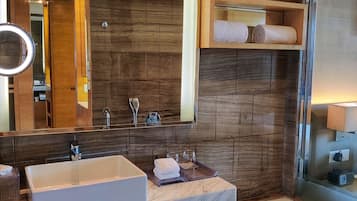 Une salle de bain moderne avec un grand miroir, deux lavabos, une baignoire, des meubles en bois et un porte-serviettes.