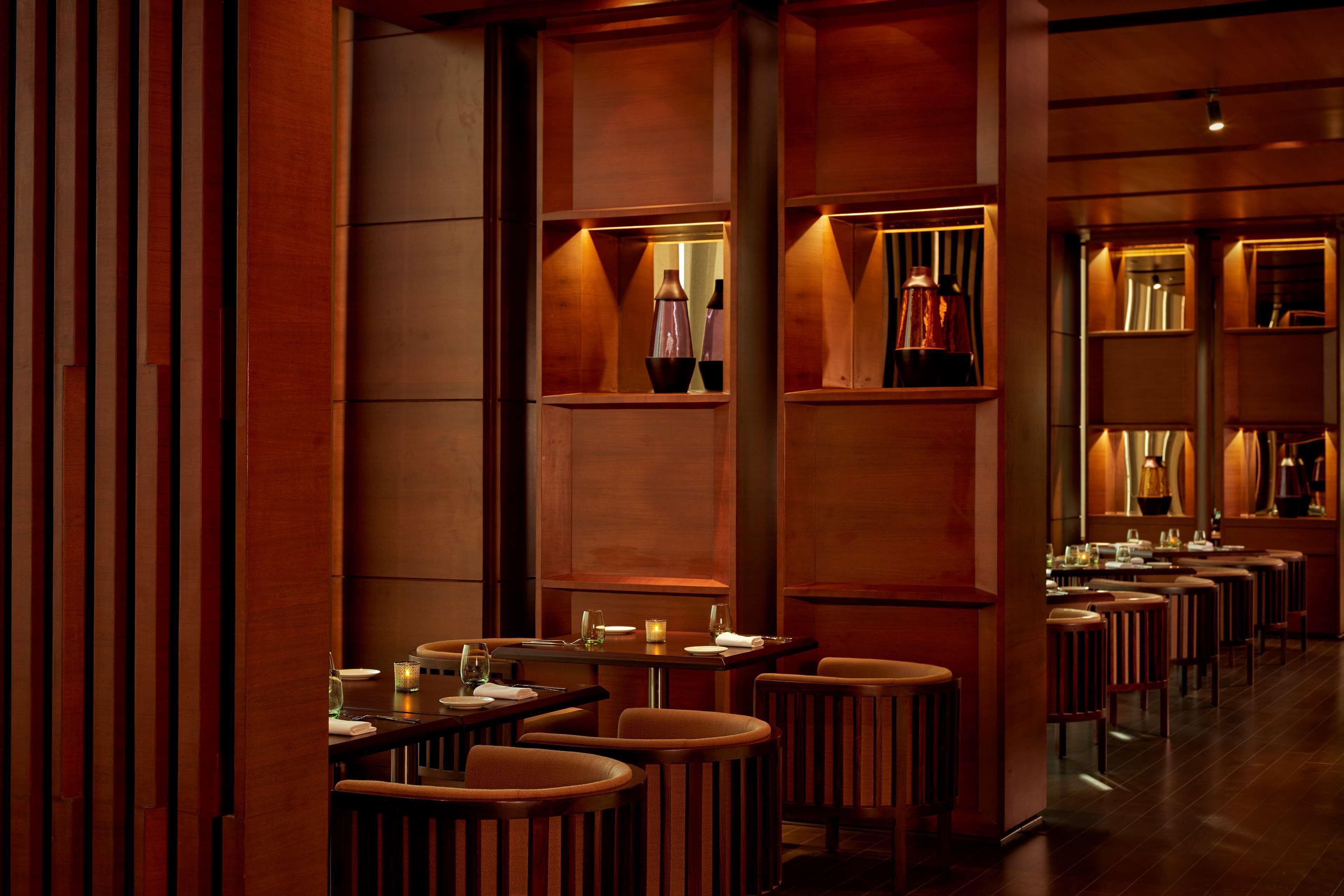 A dimly lit restaurant with wooden paneling and multiple tables and chairs.