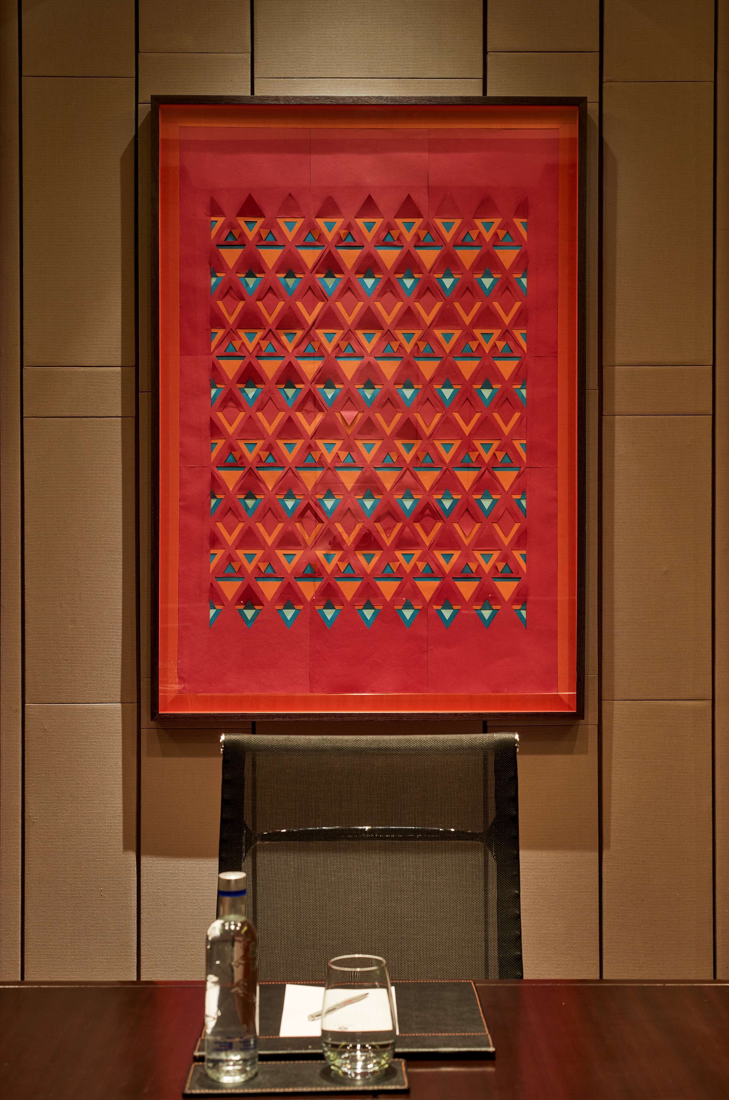 A framed artwork with a geometric pattern on a wall.