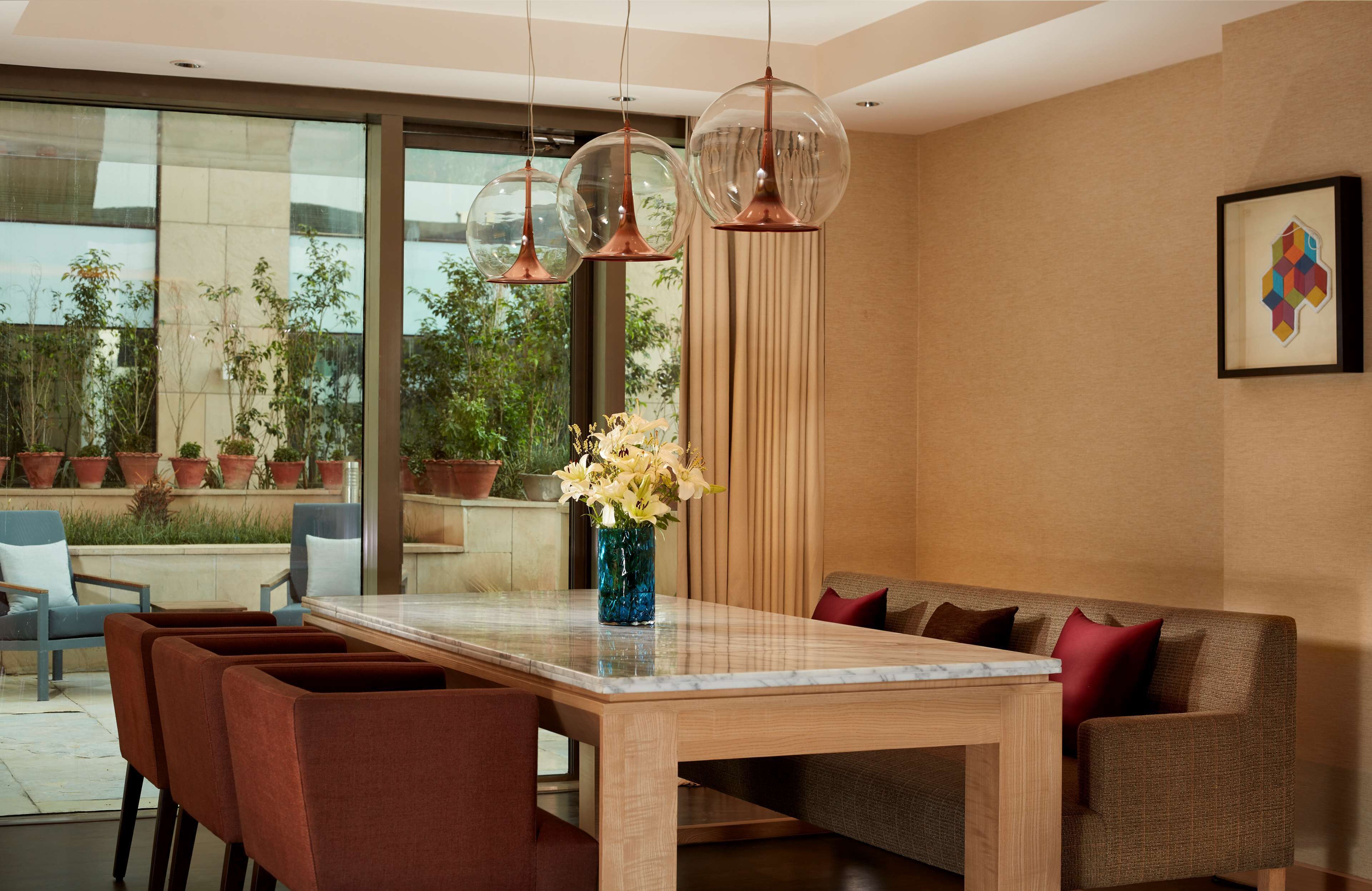 Un comedor moderno con una mesa de madera, sillas tapizadas en rojo y un jarrón de flores.