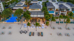 A resort with multiple buildings, a swimming pool, and a beach area with sun loungers and umbrellas. - Zemi Beach House, LXR Hotels & Resorts (Shoal Bay)