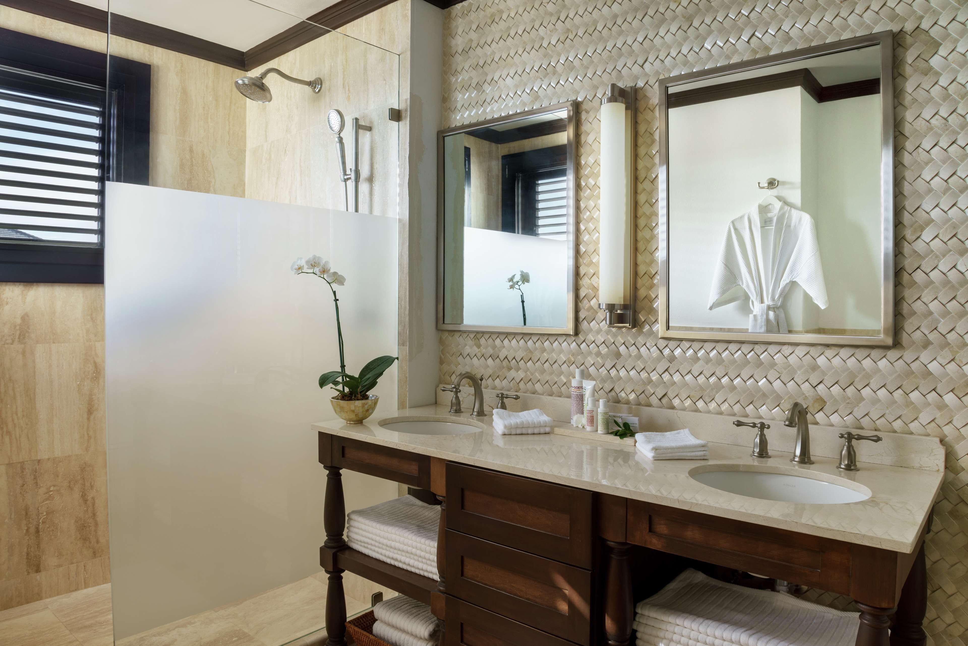 A bathroom with two sinks, a large mirror, and a potted plant.