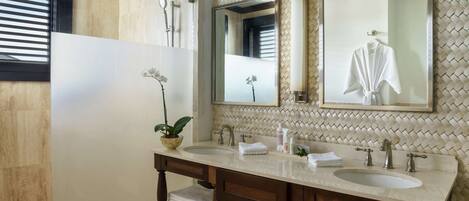 A bathroom with two sinks, a large mirror, and a potted plant.