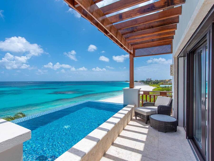 Zona junto a la piscina con vistas al océano, una pérgola y mobiliario de exterior.