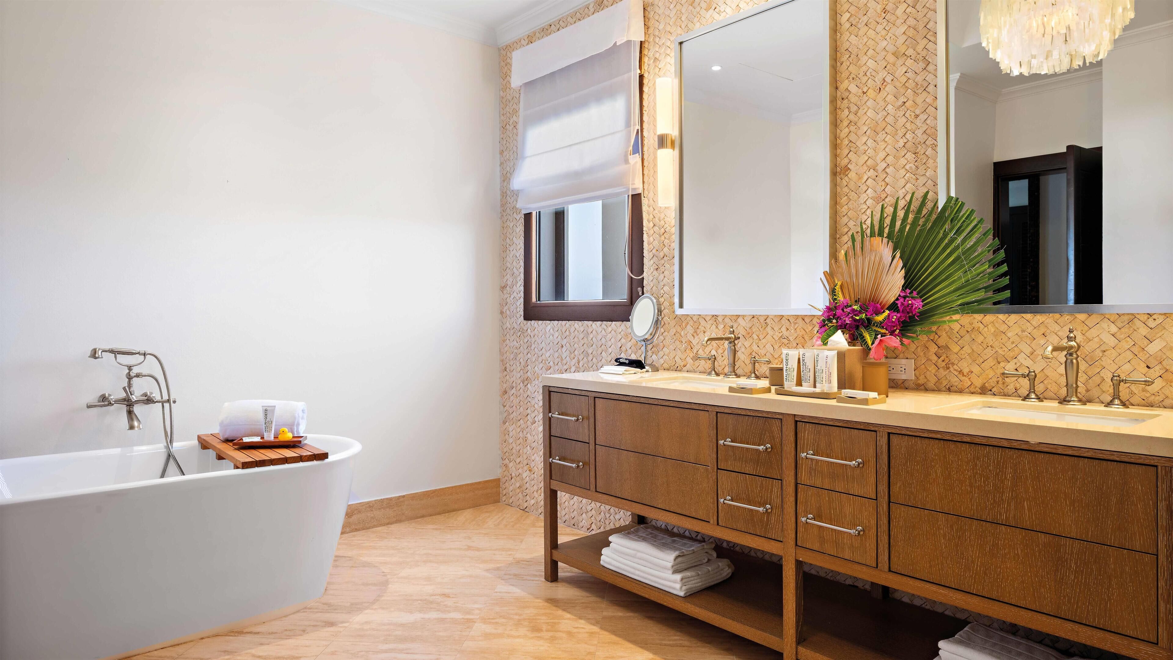 A modern bathroom with a freestanding bathtub, a vanity with a large mirror, and a wooden cabinet.