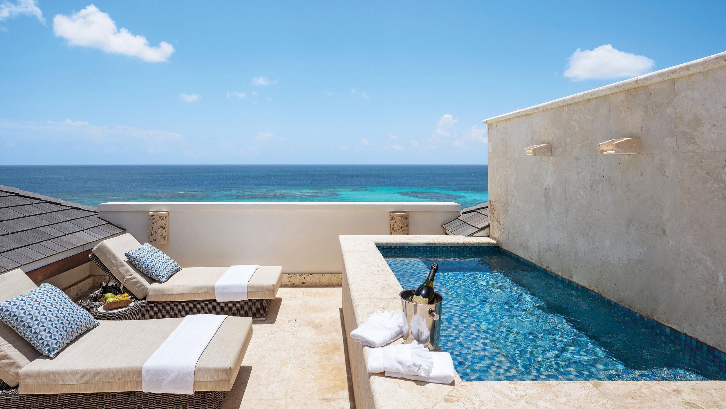 Ein Poolbereich mit Liegestühlen und Blick aufs Meer.