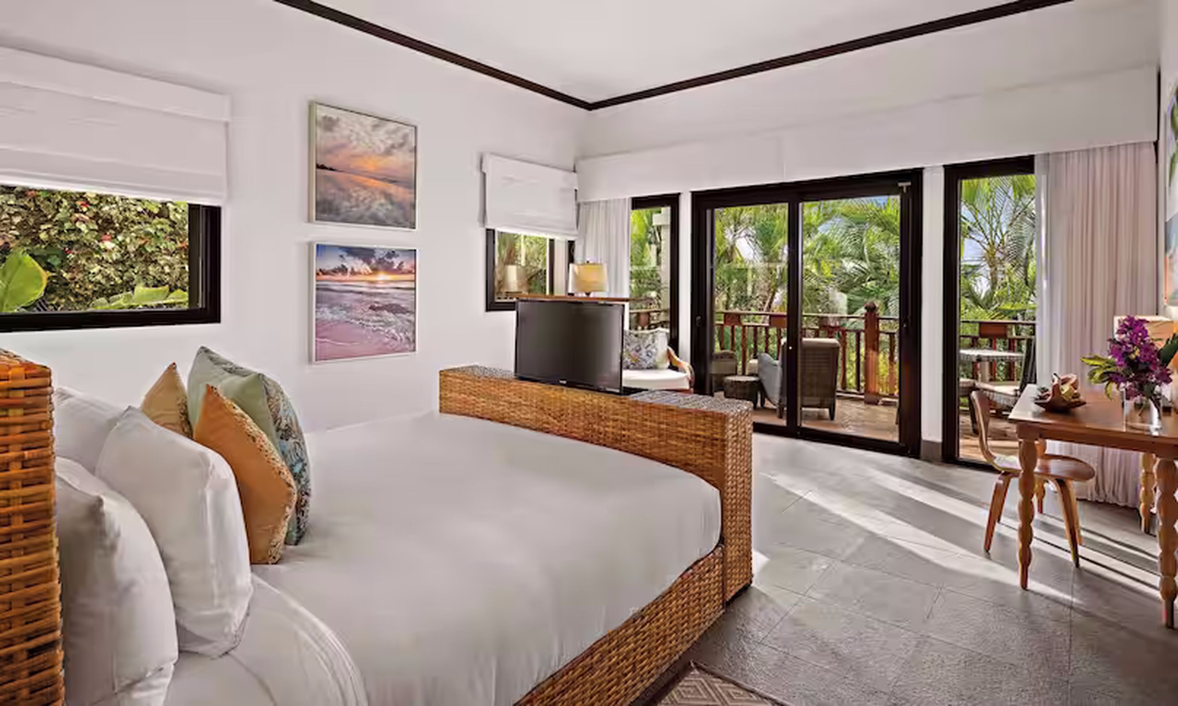 Un dormitorio moderno con una cama grande, un televisor y un balcón con mobiliario exterior.