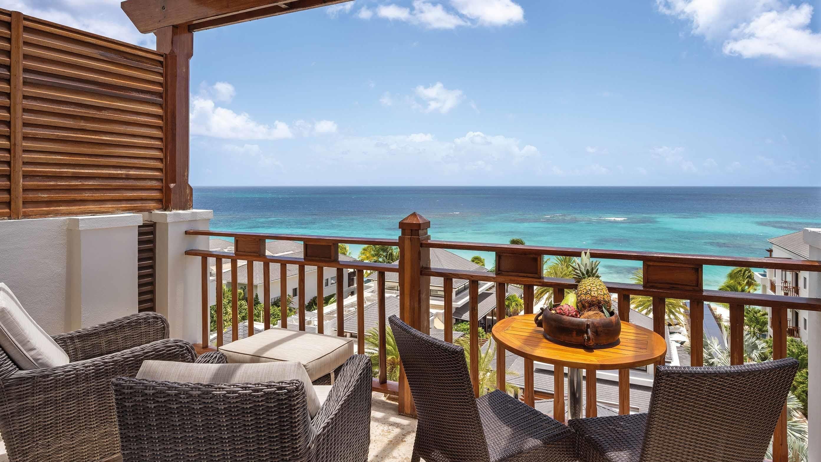 A balcony with wicker furniture and a view of the ocean.