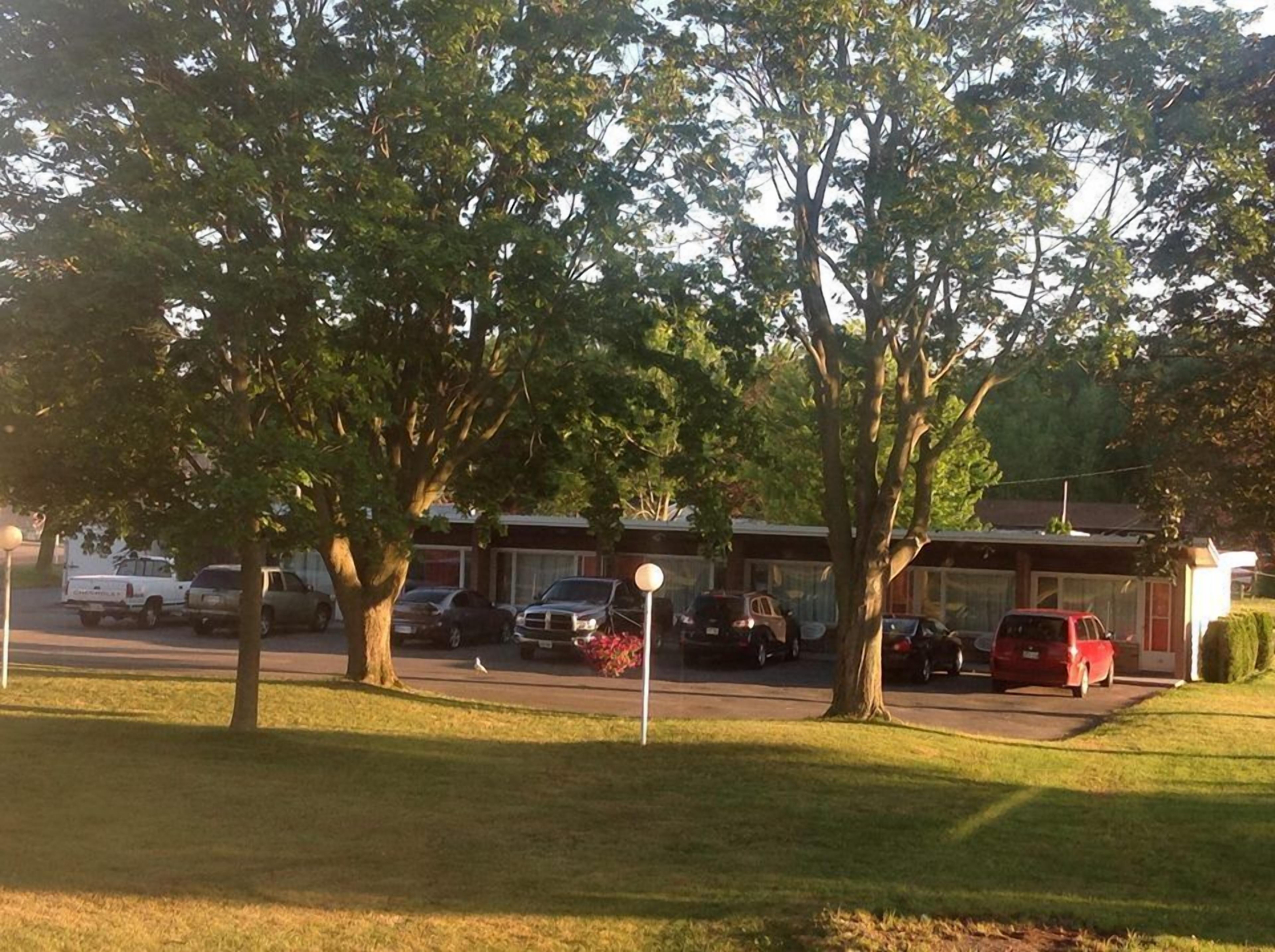 A parking lot with several cars, trees, and a building with a garage.