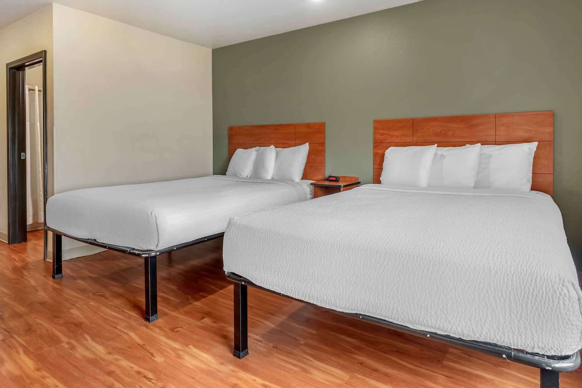 A hotel room with two beds, wooden headboards, and a nightstand.