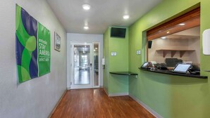 Ein Hotelgang mit einer Rezeption, einer grünen Wand und einem Holzboden.